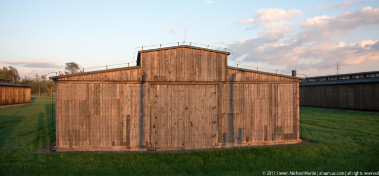 Frontal view of a weathered wooden barrack end wall with stepped roof profile at Auschwitz II-Birkenau.