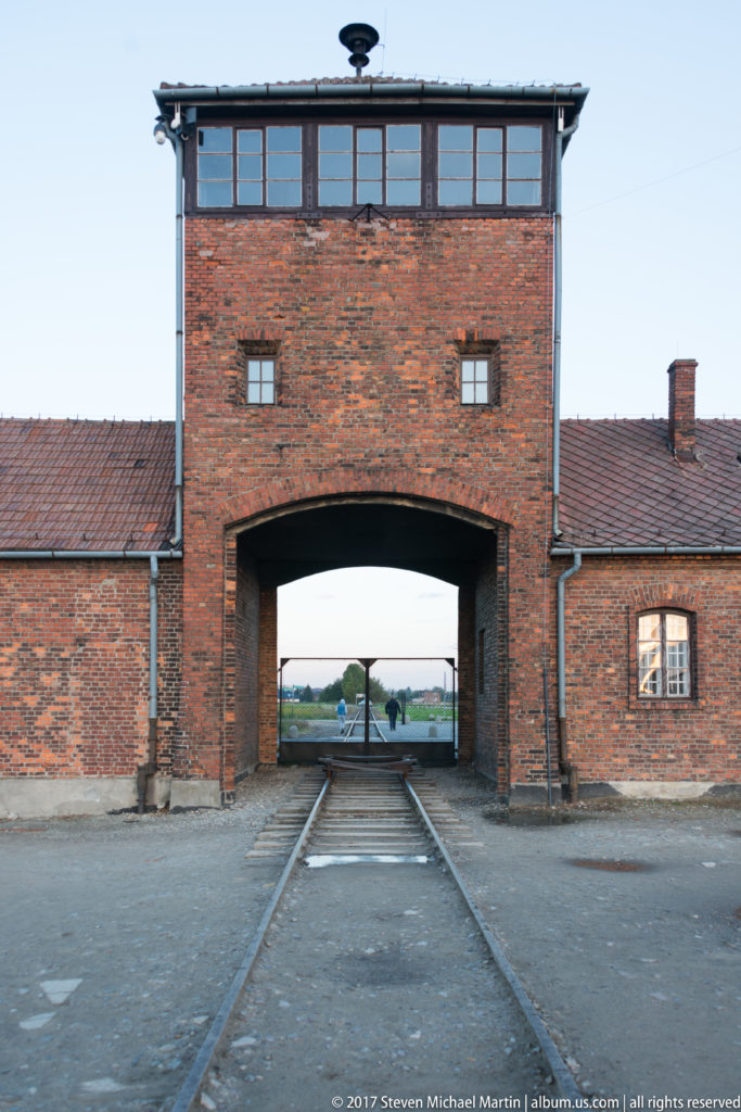 Railway tracks passing through the central arch of the brick entrance gatehouse at Auschwitz II-Birkenau.