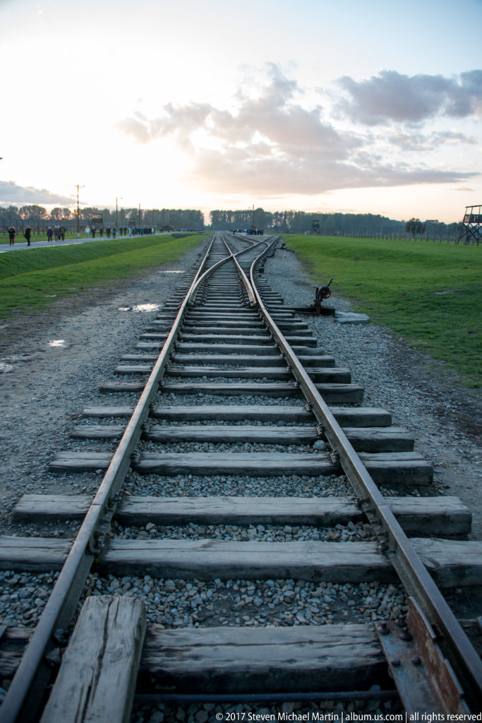 Railway tracks and a switch extending across the open grounds inside Auschwitz II-Birkenau.