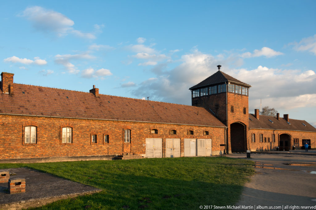Long brick barrack building with a central windowed tower and passage at Auschwitz II-Birkenau.