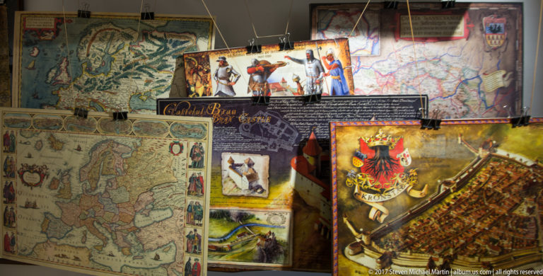 Display of historic-style maps, heraldic imagery, figures, and regional graphics associated with Bran and Transylvania.