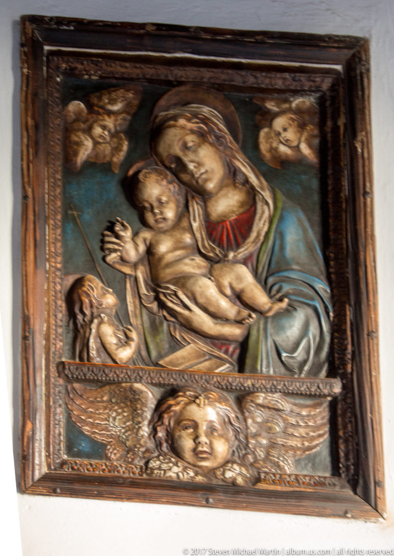 Framed relief of the Virgin Mary holding the Christ Child, with small angelic figures around them.