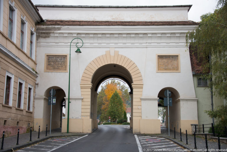 Șchei Gate in Brașov with one tall central arch and two smaller side openings across the roadway.
