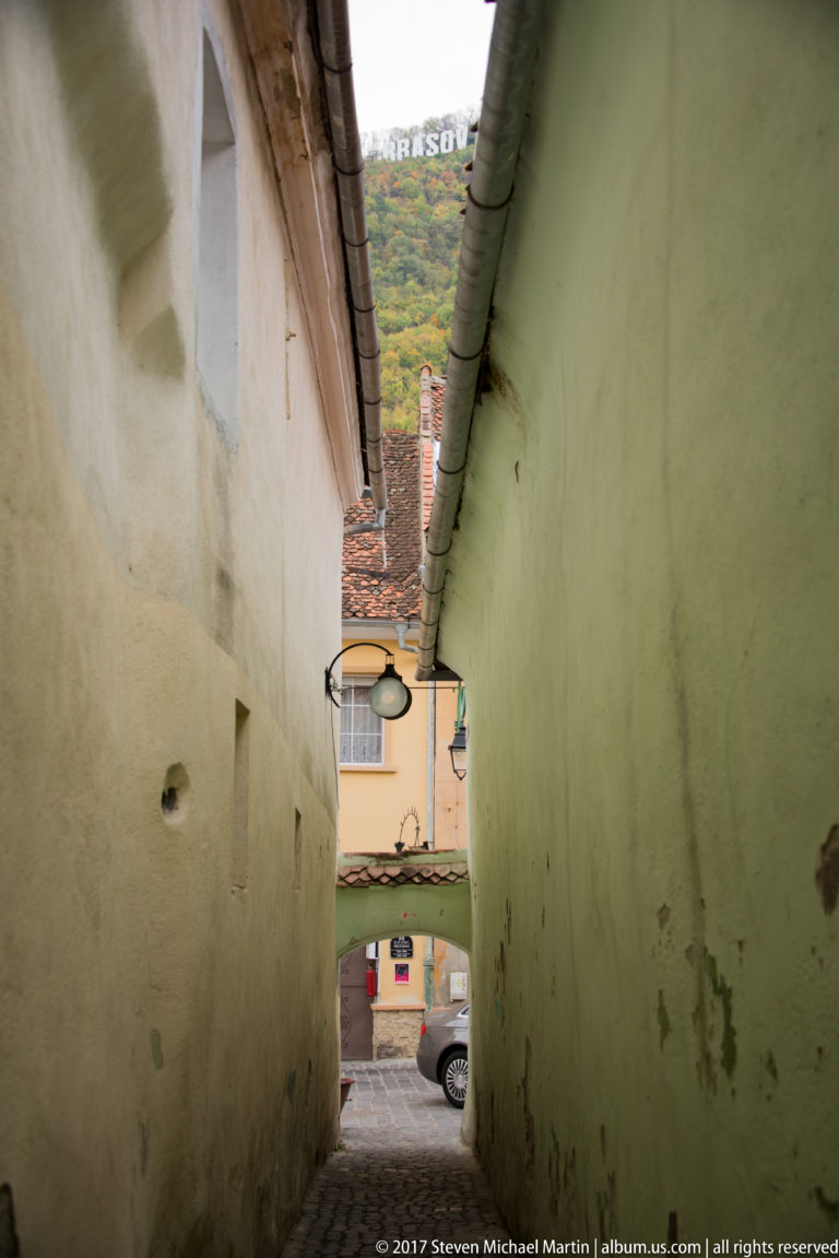 Strada Sforii, a very narrow pedestrian passage between tall pale plaster walls in historic Brașov.