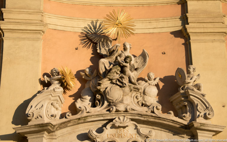 Baroque angel group with gilded Eye of Providence, scrollwork, and the inscription “TRES UNUM SUNT.”