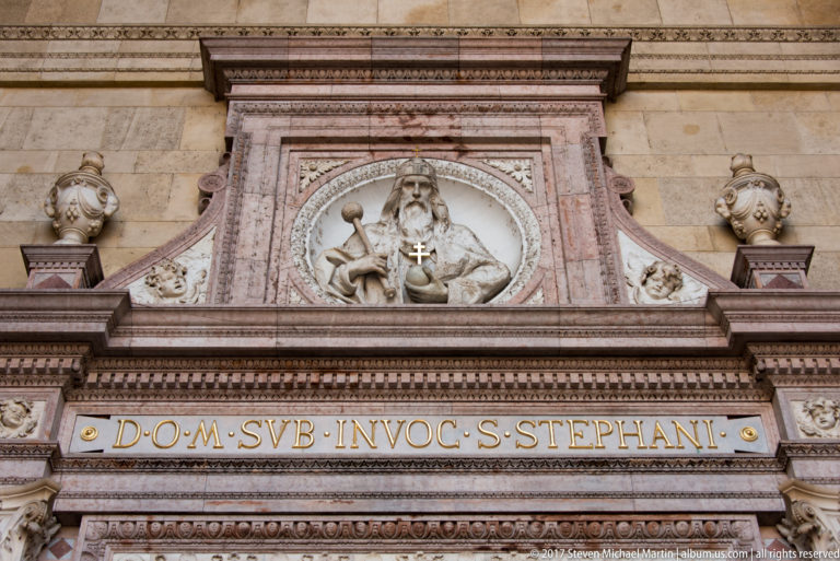Relief of a bearded sacred figure above the Latin dedication to Saint Stephen on the basilica façade.