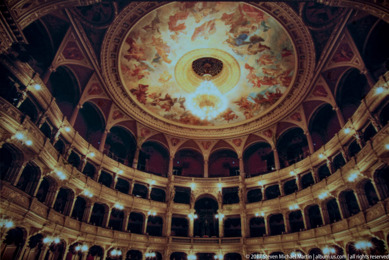 Curving gilded opera boxes beneath a large painted dome in the Hungarian State Opera House auditorium.