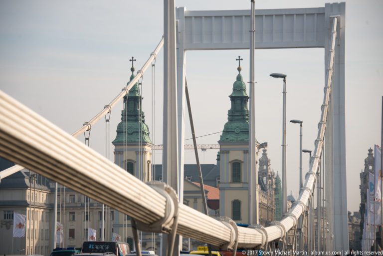 White cables of Elisabeth Bridge frame twin church towers on the Pest side of the Danube.