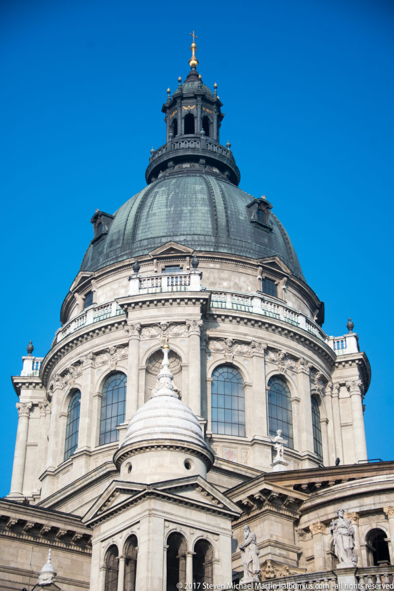 Low-angle exterior of St. Stephen’s Basilica showing the large dome, arched windows, pilasters, and sculpted figures.