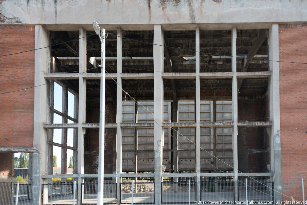 Open concrete-frame industrial building with brick walls and exposed floors near the Corvin Castle approach.