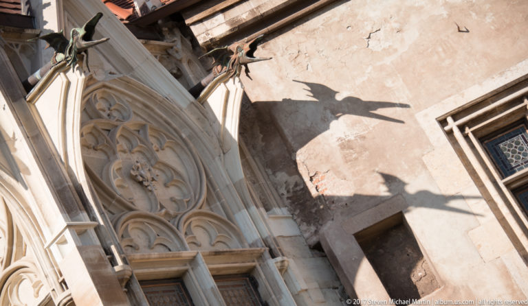 Close detail of carved Gothic tracery and pointed stone moldings against weathered castle masonry.