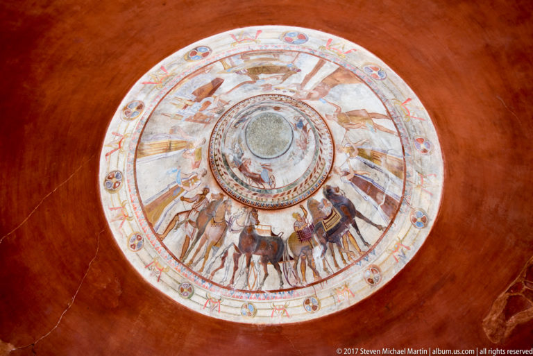 Oblique view of the circular painted dome showing concentric rings of chariots, horses, human figures, and ornamental motifs.
