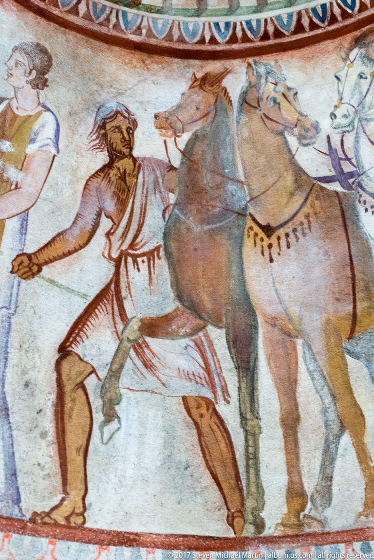 Painted bearded attendant walking beside two bridled horses with decorated chest straps in a horizontal frieze.