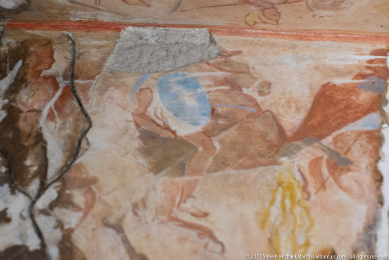 Fragmentary wall painting with several human figures and part of a horse in red, ochre, blue, and yellow tones.