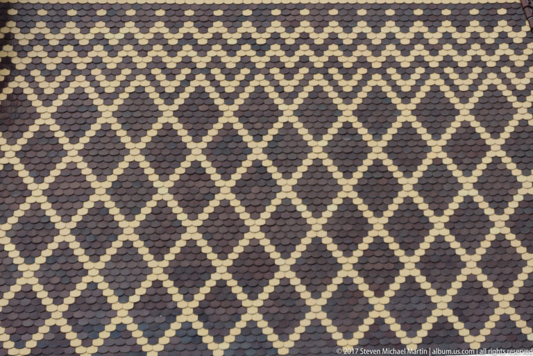 Close view of dark and pale roof tiles arranged in a repeating diamond lattice on St. Elisabeth Cathedral.