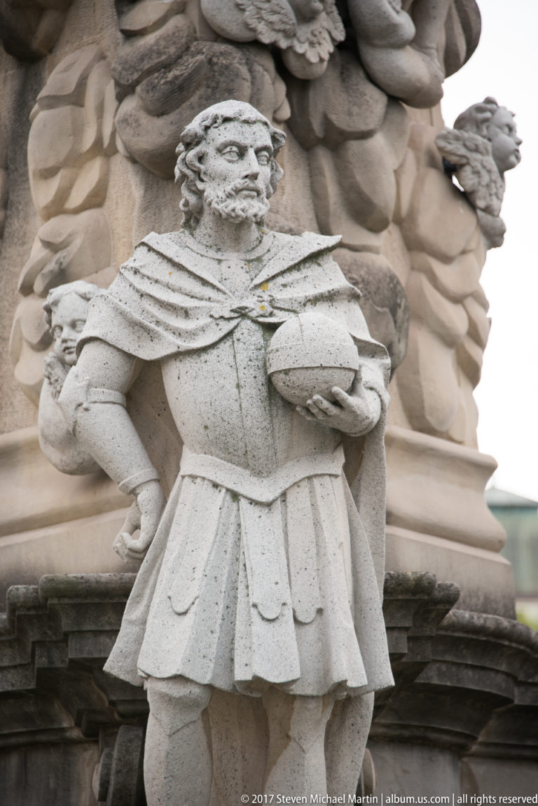 Carved stone figure in historical dress set against an ornate sculptural façade in Košice.