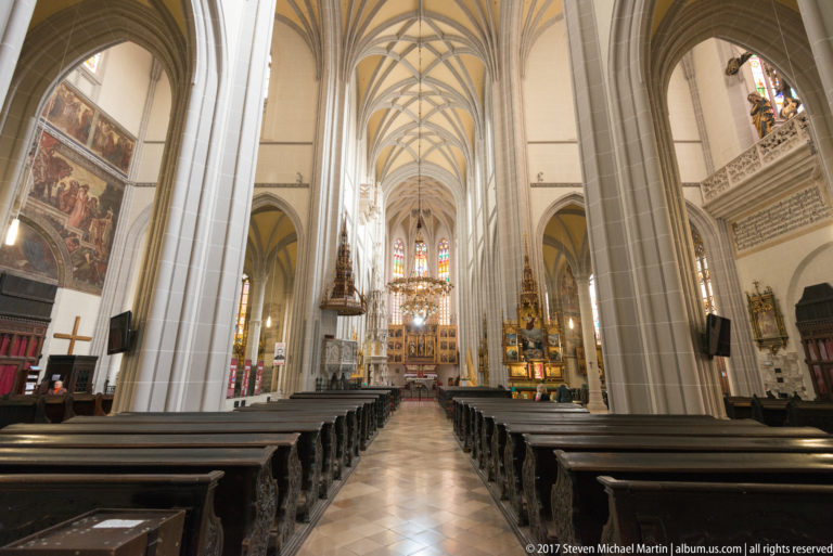Central nave of St. Elisabeth Cathedral with ribbed vaults, clustered piers, dark pews, stained glass, and high altar.