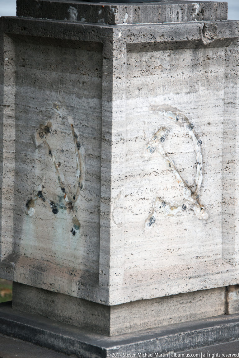 Weathered stone wall blocks with faint incised circular and horseshoe-shaped marks.
