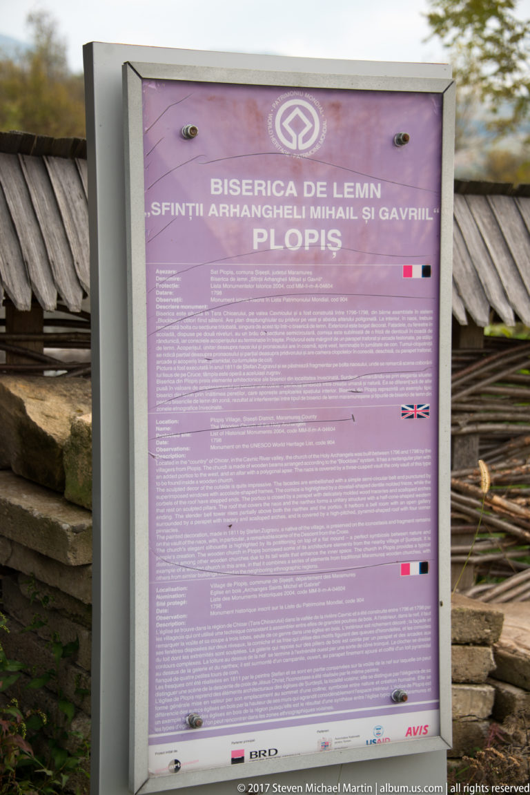 Multilingual information panel naming the Wooden Church of the Holy Archangels Michael and Gabriel at Plopiș.