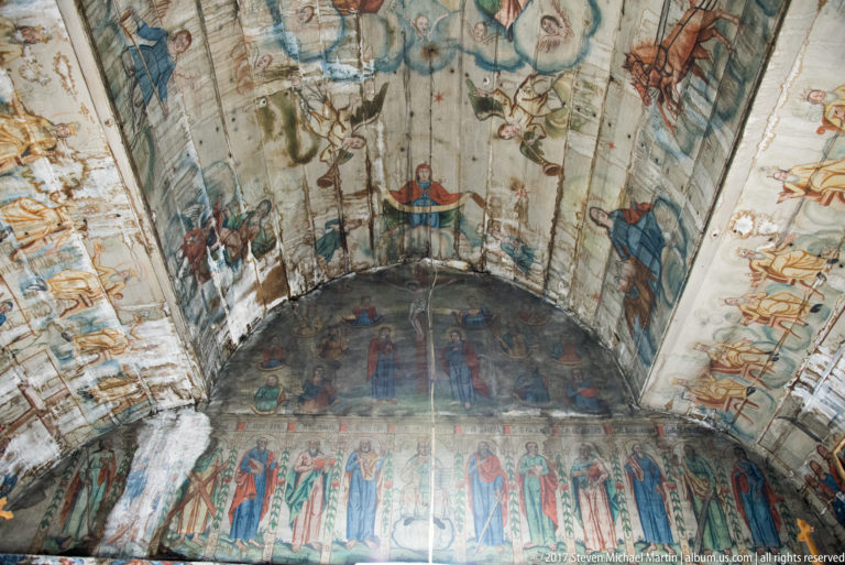 Curved wooden vault covered with rows of religious figures, angels, and narrative scenes inside the Plopiș church.