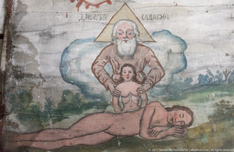 White-bearded divine figure above a small woman beside the sleeping Adam in a painted Creation of Eve scene.