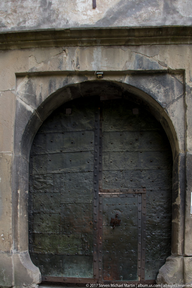 Massive dark wooden double doors beneath a broad stone arch at Orava Castle.