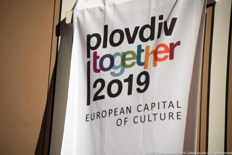 White fabric banner reading “plovdiv together 2019” and “EUROPEAN CAPITAL OF CULTURE” in multicolored lettering.