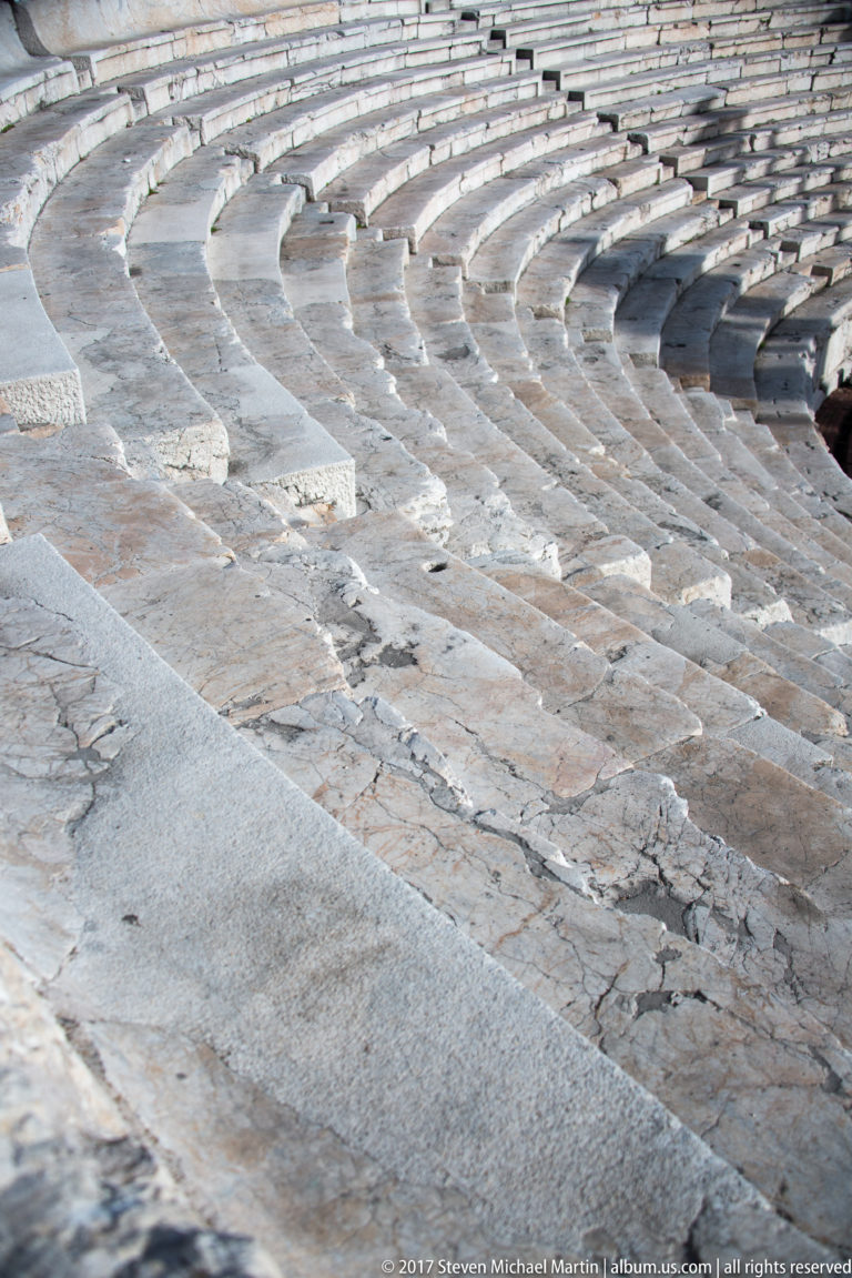 Oblique close view across curved rows of pale, cracked stone seats in Plovdiv’s ancient theatre.