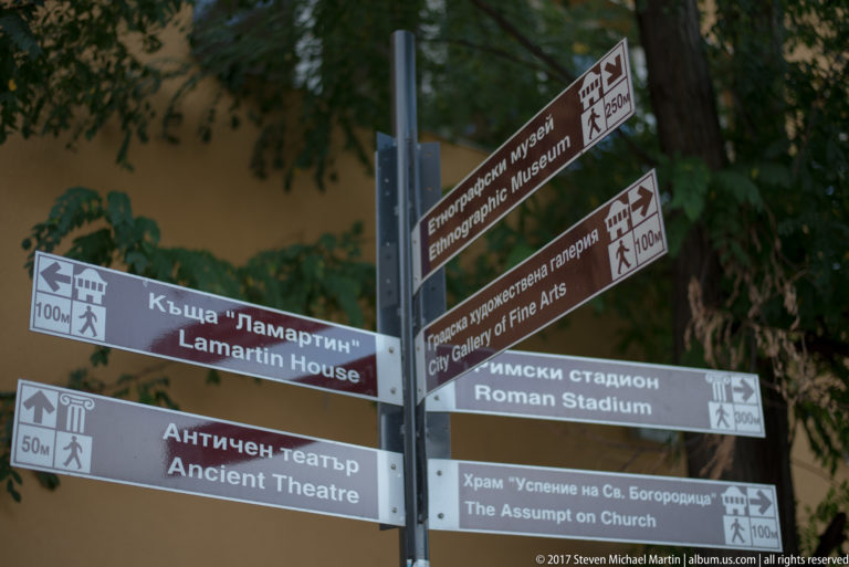 Bilingual pedestrian signs point toward Plovdiv’s Ancient Theatre, Roman Stadium, museums, gallery, church, and Lamartine House.