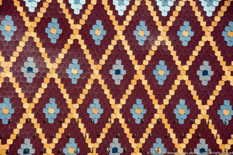 Close-up of multicolored glazed roof tiles arranged in repeating diamonds and flower-like geometric patterns.