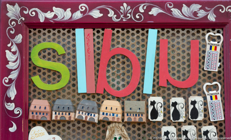 Souvenir rack with colorful “sibiu” letters, miniature house magnets, and Romania-themed designs.