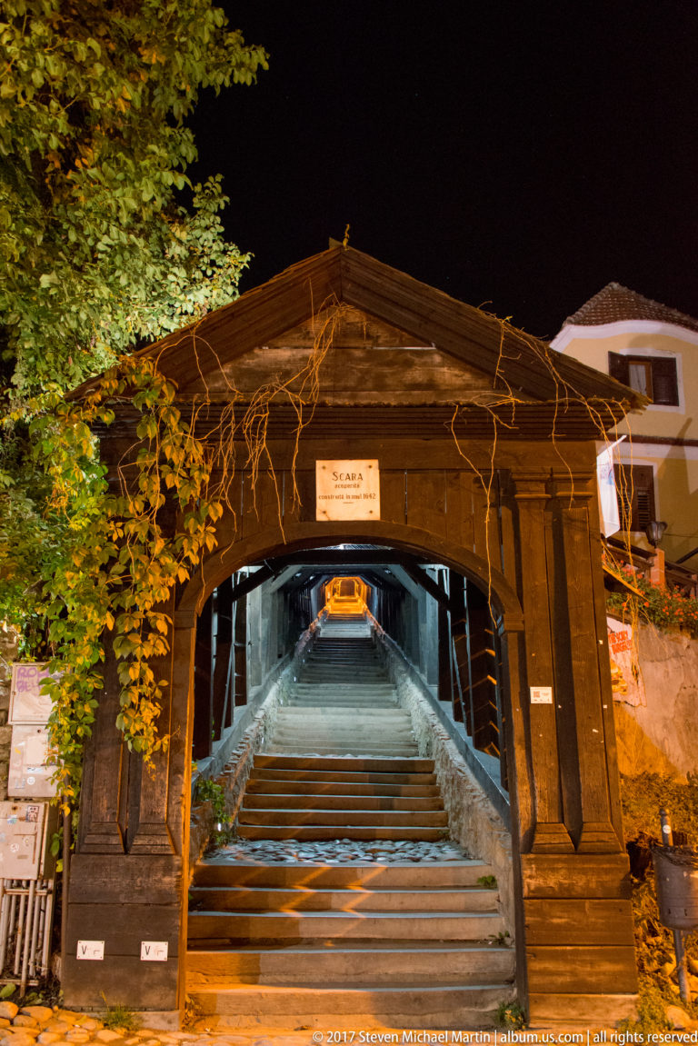 Wooden gabled entrance to Sighisoara's Scholars' Stairs with the long covered staircase visible inside.