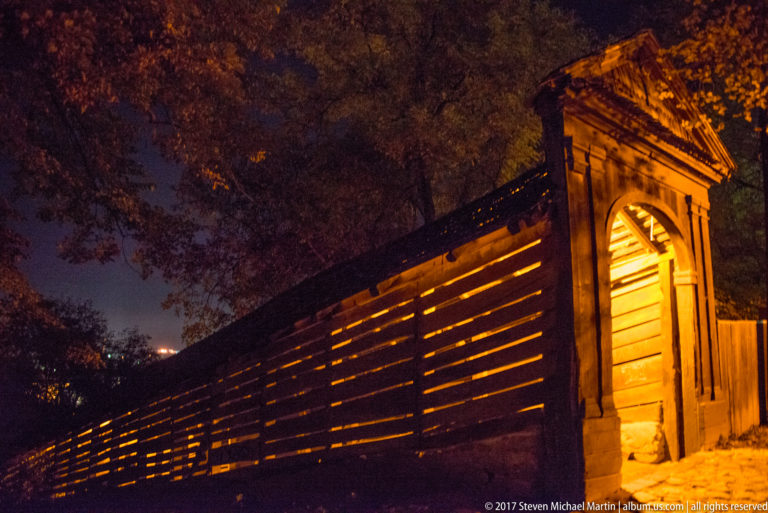 Timber entrance and long illuminated interior of Sighisoara's covered Scholars' Stairs rising steeply uphill at night.