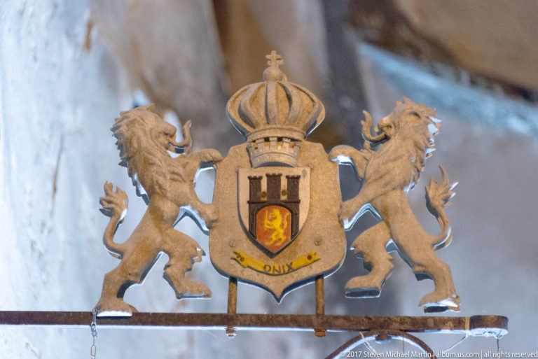 Crowned metal coat of arms with a central shield and two rampant lion supporters.