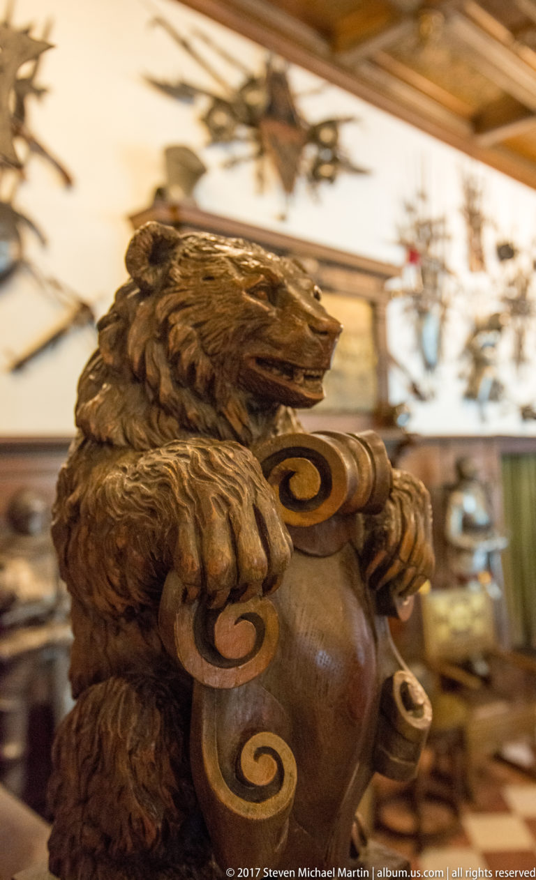 Close view of a carved wooden animal figure with prominent paws resting on curled decorative scrolls.