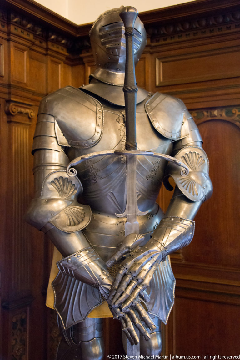 Close view of a polished suit of plate armor with helmet, shoulder plates, articulated arms, and gauntlets.
