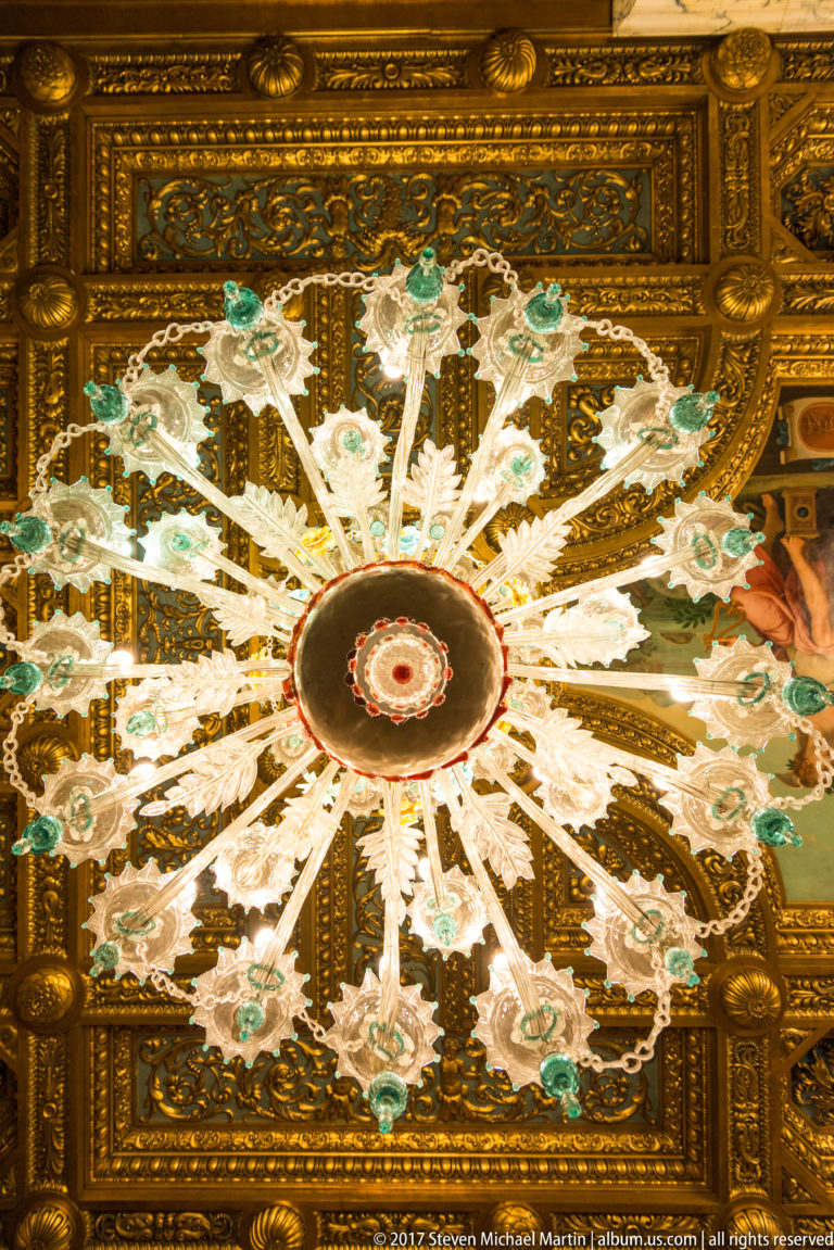 Radial white, green, and red floral ceiling ornament centered within a richly gilded carved field.