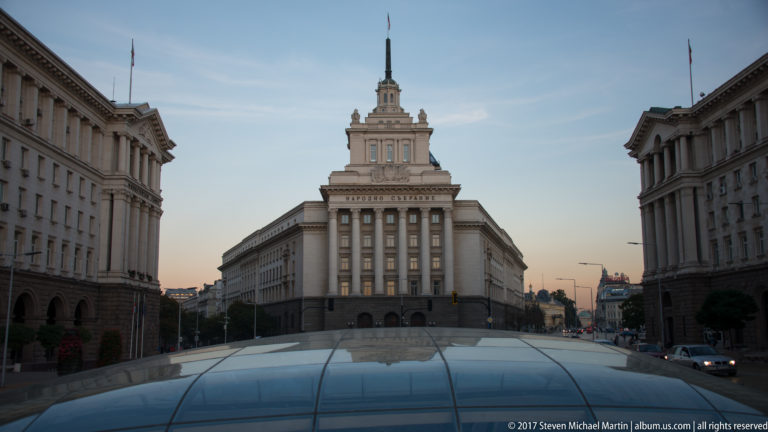 Monumental former Party House at Sofia’s Largo with central tower, National Assembly inscription, and glass archaeological canopy in front.