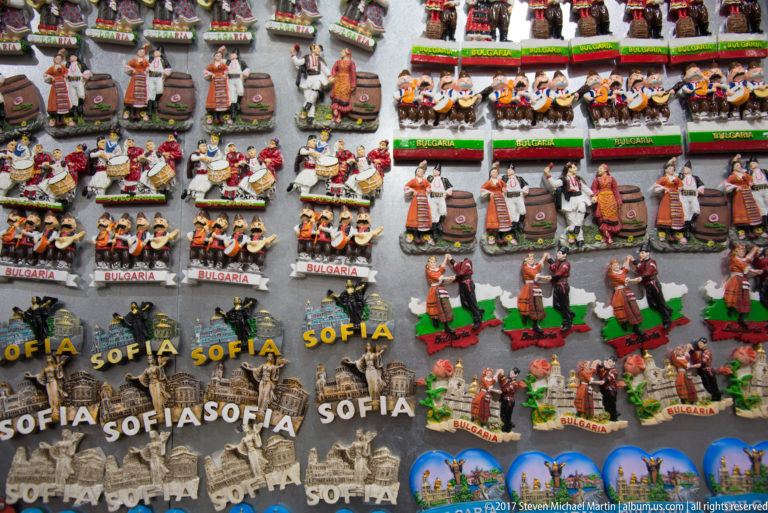 Rows of colorful Sofia and Bulgaria souvenir magnets with folk figures, buildings, monuments, and raised place-name lettering.