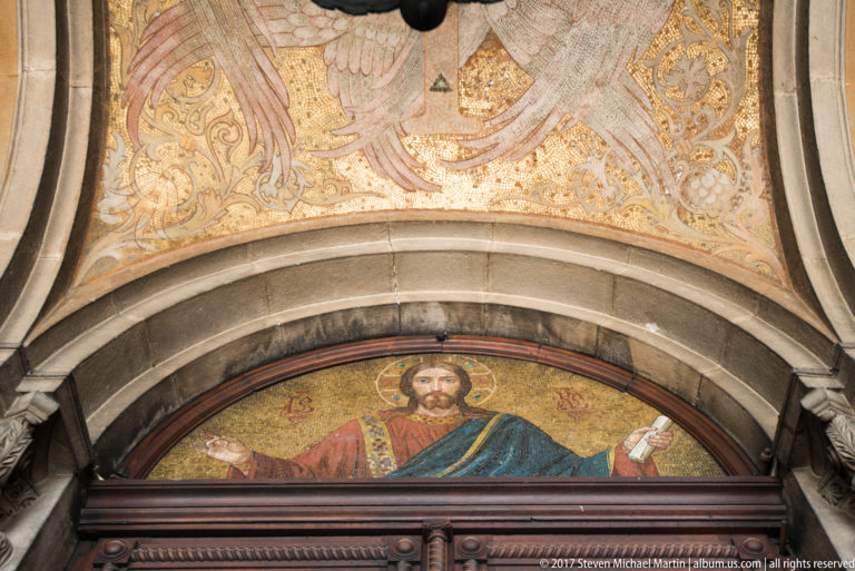Gold-ground mosaic of Christ in a semicircular arch above a doorway at Alexander Nevsky Cathedral.