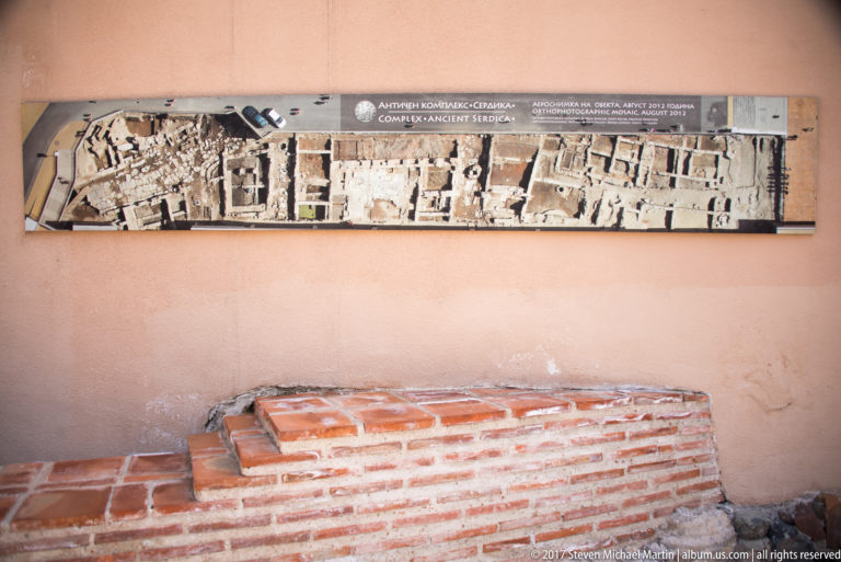 Low brick archaeological feature beneath an interpretive plan of the Ancient Serdica complex in Sofia.