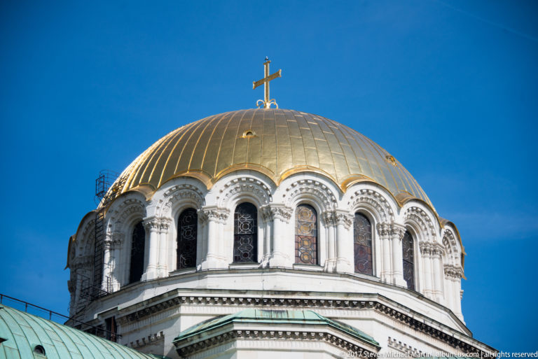 Close view of Alexander Nevsky Cathedral’s gilded dome, arched drum windows, cross, and green lower roofs.