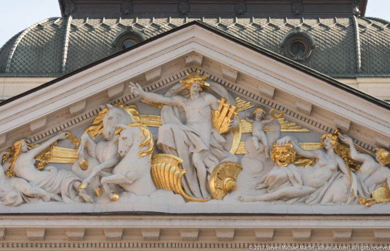 Close view of Ivan Vazov National Theatre pediment with pale allegorical figures and gilded theatrical ornaments in relief.