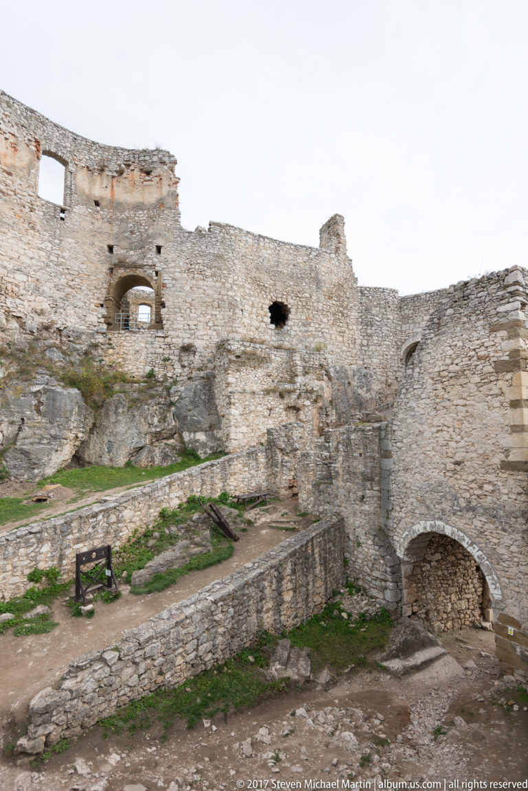 Interior castle ruins with arched openings, terraced stone walls, and uneven paths.