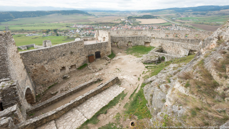 High view over inner castle walls and courtyard toward the lower fortifications and settlement beyond.