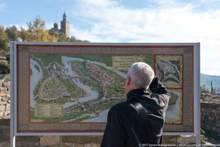 Visitor viewed from behind studying a large illustrated reconstruction map at the fortress.