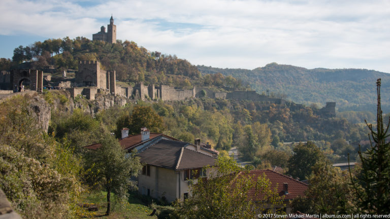 Long stone fortress wall with towers extending across an autumn hillside above nearby houses.