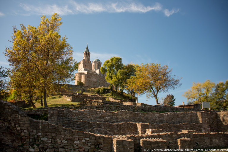 Patriarchal Church of the Ascension of Christ above stone archaeological terraces and autumn trees on Tsarevets Hill.