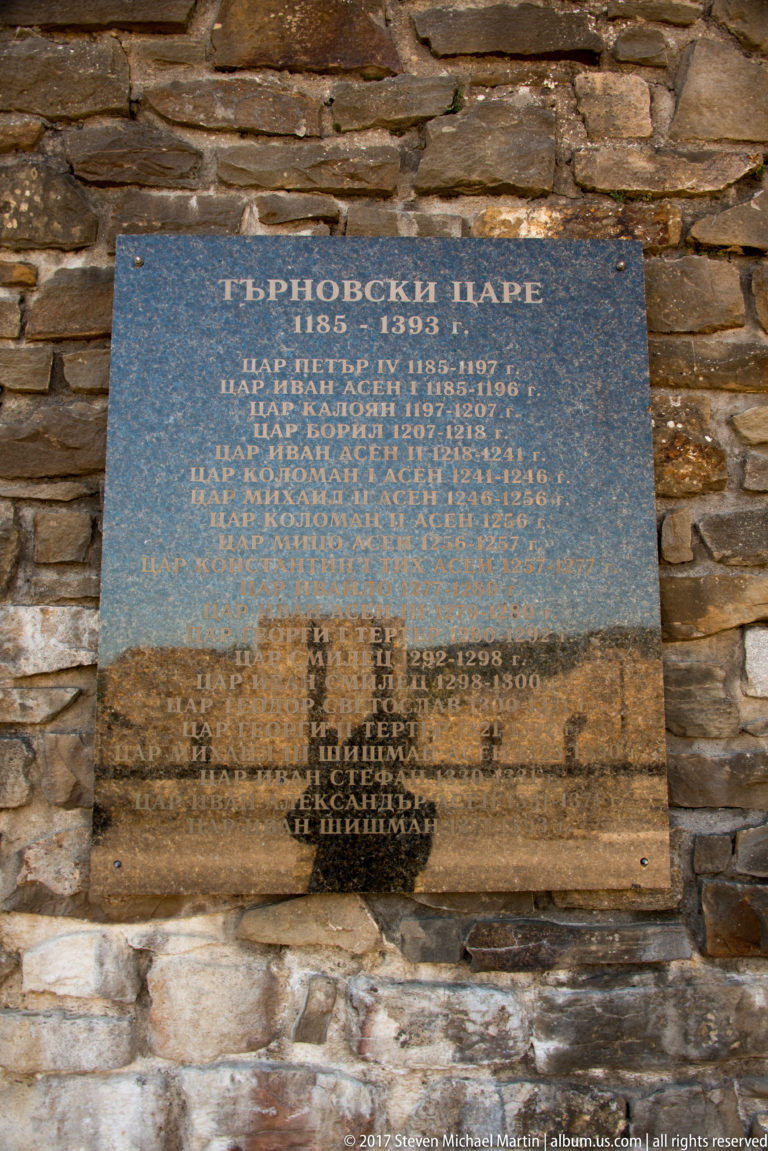 Dark polished plaque with Bulgarian Cyrillic inscription mounted on a rough stone wall.