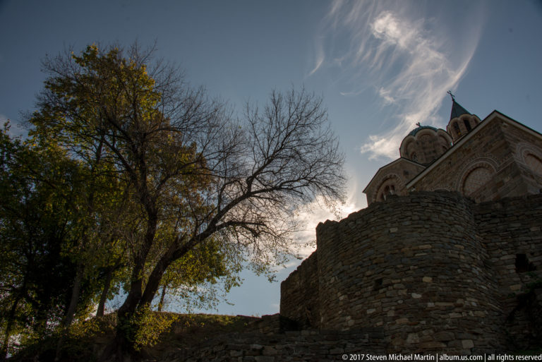 Low-angle view of the Patriarchal Church of the Ascension of Christ above a rounded stone wall and silhouetted tree.